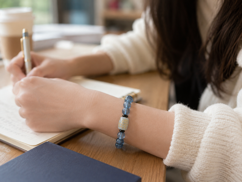 A young female student wearing a Natural Aquamarine Bracelet while writing in a notebook, with sunlight softly illuminating the study scene.