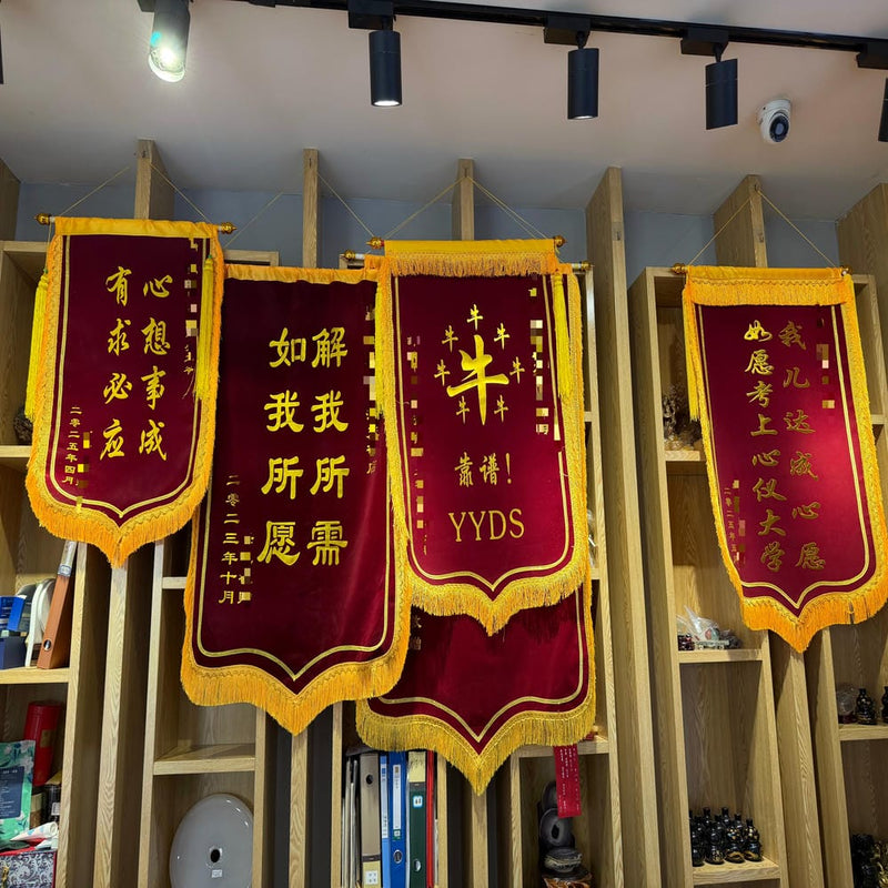 Three red and gold banners hanging on wooden shelves, showcasing client appreciation messages and testimonials for completed oracle guidance services.