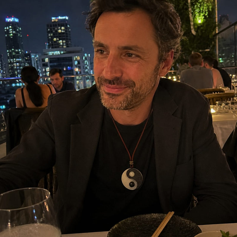 A man wearing a Taiji Yin Yang pendant during an evening dinner in a city restaurant, showing how the pendant pairs naturally with smart casual business wear.
