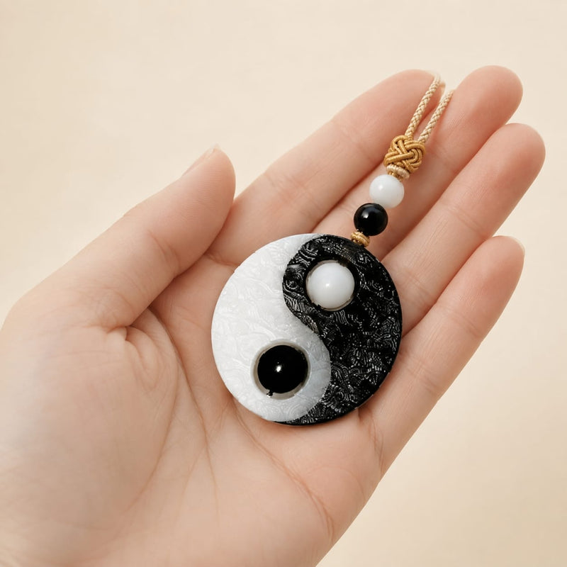 Taiji Yin Yang pendant held in a hand, showing detailed texture of black-and-white stone and beads, symbolizing focus, balance, and career alignment.