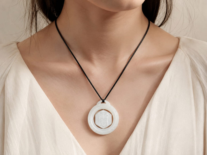 A woman wearing the Heavenly Blessing Talisman Pendant on a black cord around her neck, showing a close-up of the pendant against a soft cream outfit, highlighting its smooth finish and everyday wear elegance.