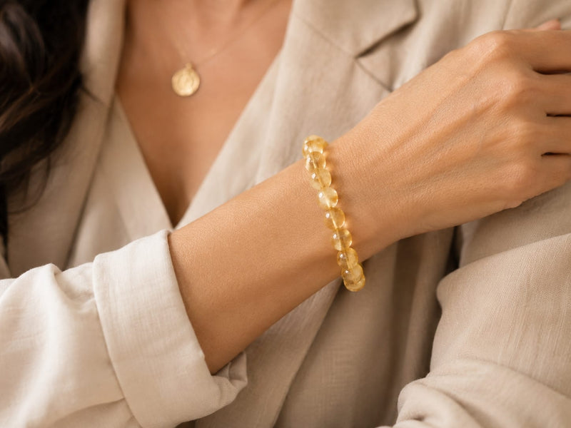 Woman wearing the citrine bracelet on her wrist paired with a neutral beige outfit, showcasing how the bracelet adds a touch of elegance and daily positivity.