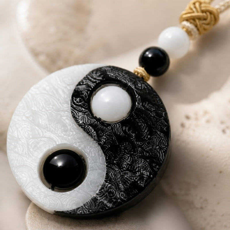 Close-up of the Taiji Yin Yang pendant resting on a stone surface, showing carved details, black onyx and white jade beads, and smooth polished finish.