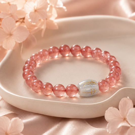 Close-up of a Natural Rhodochrosite Bracelet with Hetian Jade talisman bead, placed on a beige ceramic dish with soft pink floral accents and satin fabric background.
