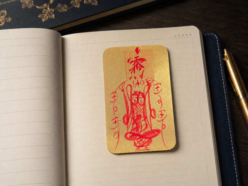 The Wenchang Wisdom & Career Talisman placed upright on an open notebook, highlighting concentration and study efficiency. The gold talisman with red calligraphy contrasts against the lined pages, creating a scholarly and serene study setting.