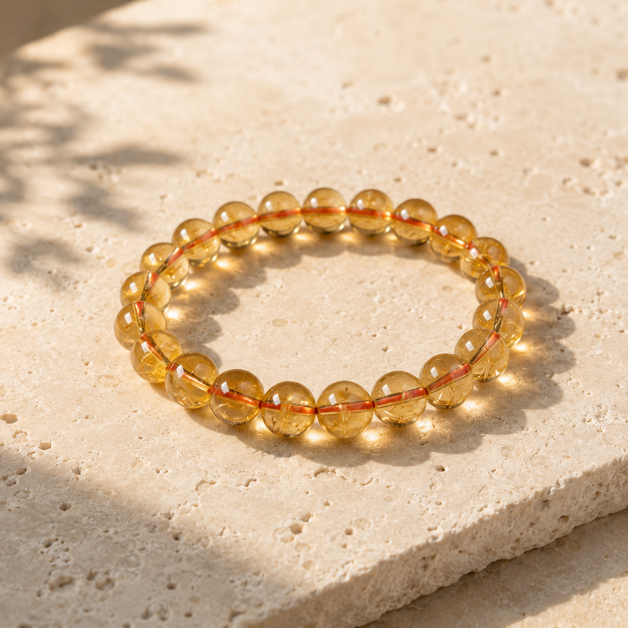 A Yellow Citrine Abundance Bracelet placed on a light stone surface in soft sunlight, showing luminous golden beads and a refined natural crystal appearance.