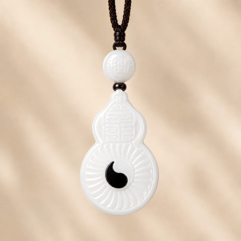 Close-up of the Vermilion Bird white jade pendant, showing detailed carvings, round bead, and black yin accent