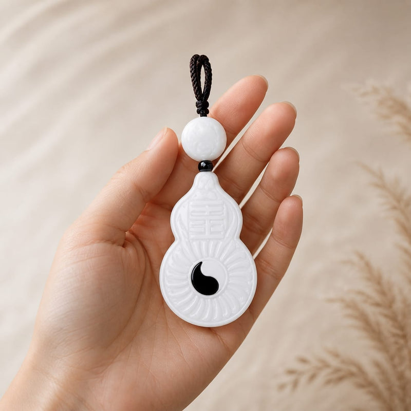 Hand holding the Vermilion Bird white jade pendant, showing the cord and pendant details, natural daylight.