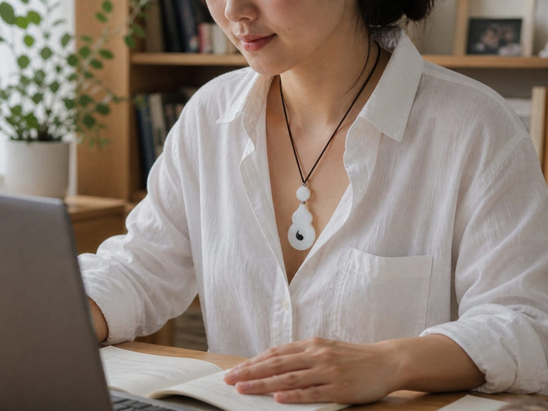 Person wearing the Vermilion Bird pendant indoors while working at a desk, showing layering potential and personal styling with casual clothing.